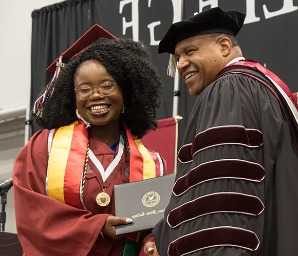 College president giving diploma to graduate